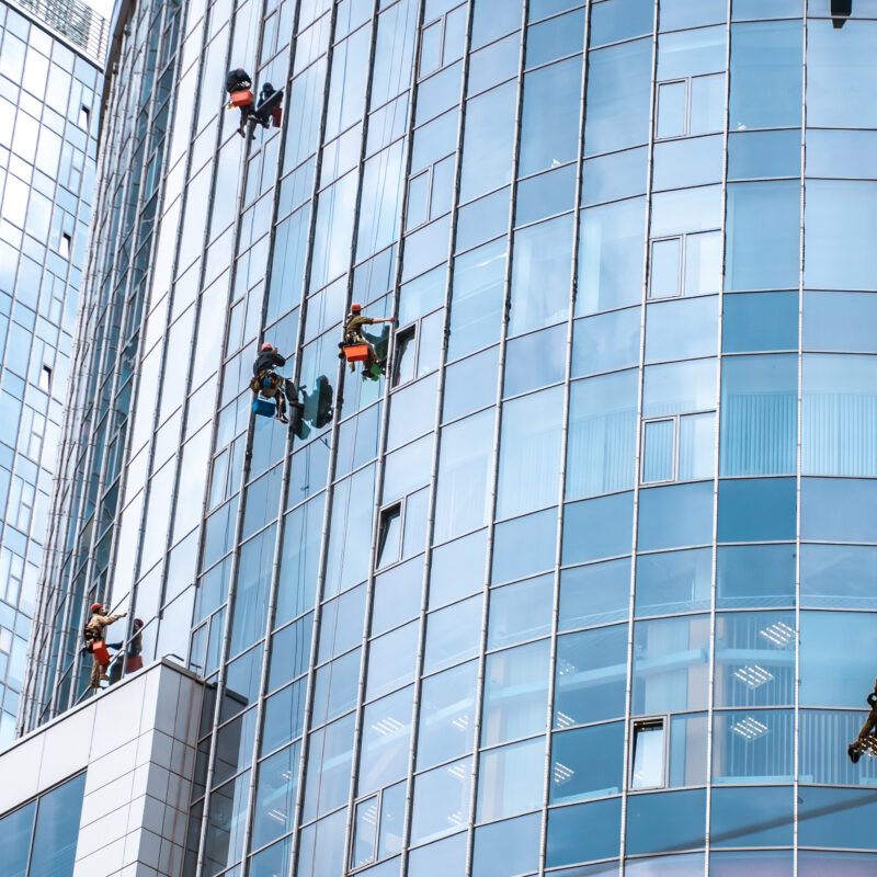 Several workers washing windows in the office building